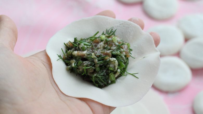 茴香馅饺子,取一张饺子皮用左手拖住，取适量馅料放到中间