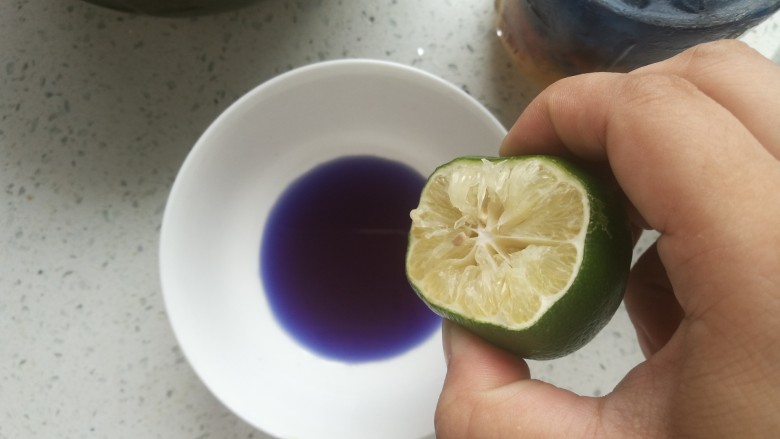 星空银耳桃胶羹,杯中蓝色加深后,过滤出蝶豆花。把液体分两份,一份加入几滴柠檬汁,颜色会变成紫色。