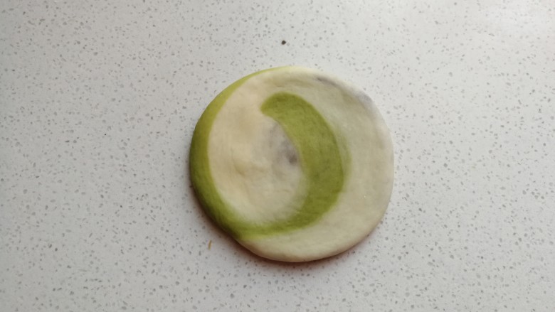 彩色风车豆沙包,取一份面团,先用手压扁,然后用擀面杖擀成厚薄适中的圆片。