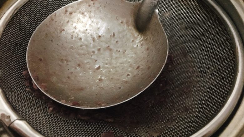 桃胶陈皮红豆沙,舀出红豆到筛子上,用大汤勺背推压红豆。