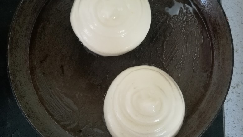 详解舒芙蕾厚松饼,用裱花袋把面糊挤到平底锅上,开小火慢煎。等到底部开始变黄,用锅铲(不要木铲)慢慢铲到底再翻过面来煎。还是小火,等底面也开始变色,再翻面。直到牙签插近松饼中心,去残渣即是熟了。装盘趁热吃。