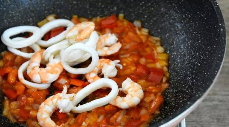 世界杯各国特色美食——西班牙海鲜烩饭,将焯熟的鱿鱼圈,虾仁,放入锅中
