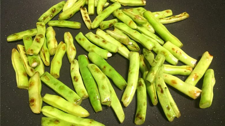 芽菜四季豆,先热锅倒少量油将四季豆煸熟透,煸至表皮出焦点,然后盛出备用。