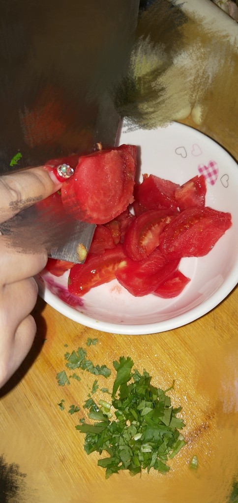 酸汤龙利鱼,将去了皮的西红柿放在手中切片,保证西红柿汤汁不会流失
