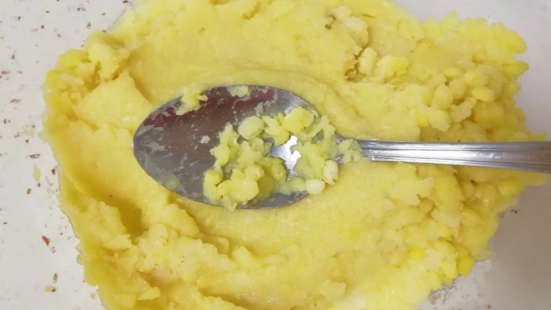 蔓越莓绿豆糕,用勺子舀一勺蒸熟的绿豆,压成泥,再舀一勺,继续压成泥...直到把蒸好的绿豆全部压完。