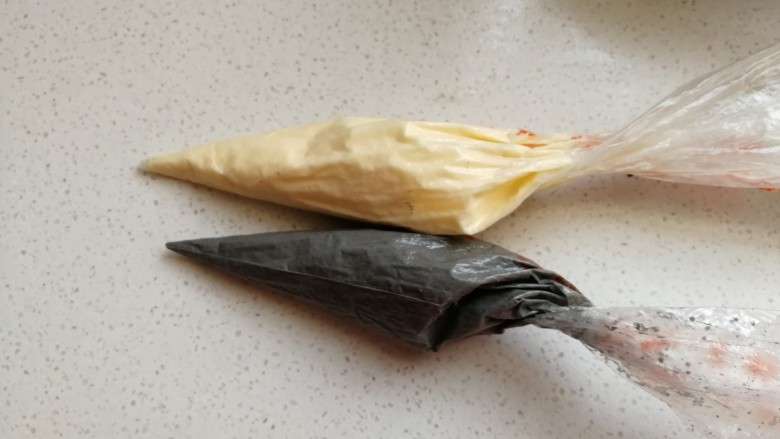 足球慕斯蛋糕卷,然后把拌好的竹炭蛋糊装入裱花袋中,再取同样分量的原色蛋糊也装入裱花袋备用。