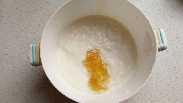 足球慕斯蛋糕卷,吉利丁片用水泡软捞起加入酸奶中,再放入微波炉加热十秒后搅拌至吉利丁与酸奶完全融合。