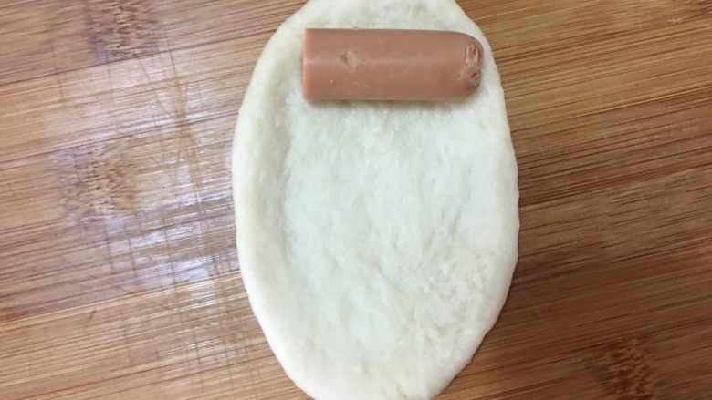 肉松香肠包,揉捏排气后取一个小面团,擀扁成如图所示