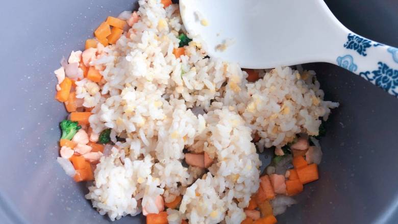 【宝宝辅食】三文鱼耳光炒饭,最后放入米饭,用勺子背部把米饭压开,与配菜一起翻炒均匀即可