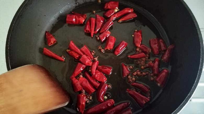 花椒鸡丁,锅中留30亳升的油,放入花椒和干辣椒炒香。