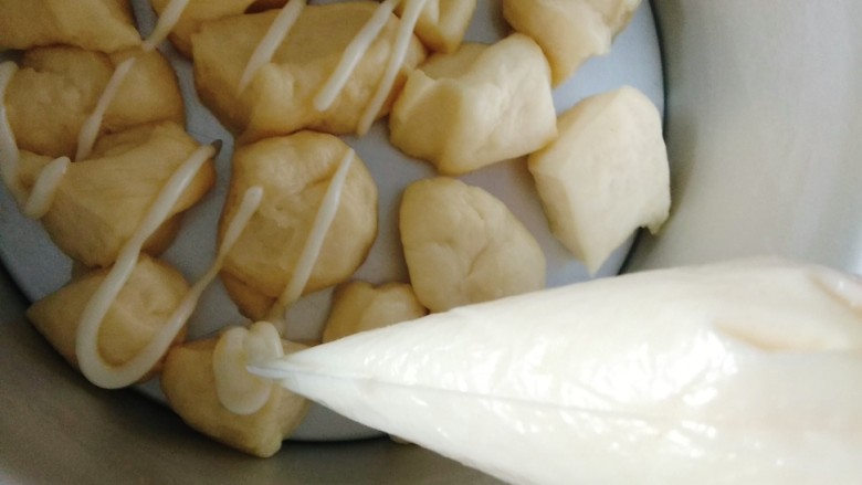 海苔脆肉松手撕面包~,我用的是戚风模具,把模具里摆一层面团块,每个之间都留出来空间,给二次发酵留好空间,把装在一次性裱花袋里的秘制酱汁的裱花袋前端剪一个小小的口子,把酱汁淋挤在面团块上,可以根据喜好,多淋一些;