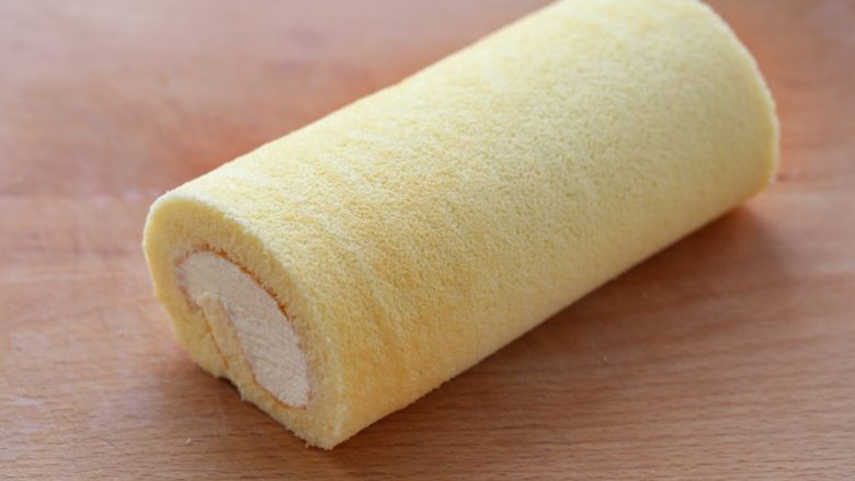 奶油蛋糕卷,用擀面杖反卷油纸带动蛋糕卷起来,包好后放进冰箱冷藏两个小时左右定型,取出切成小块食用即可