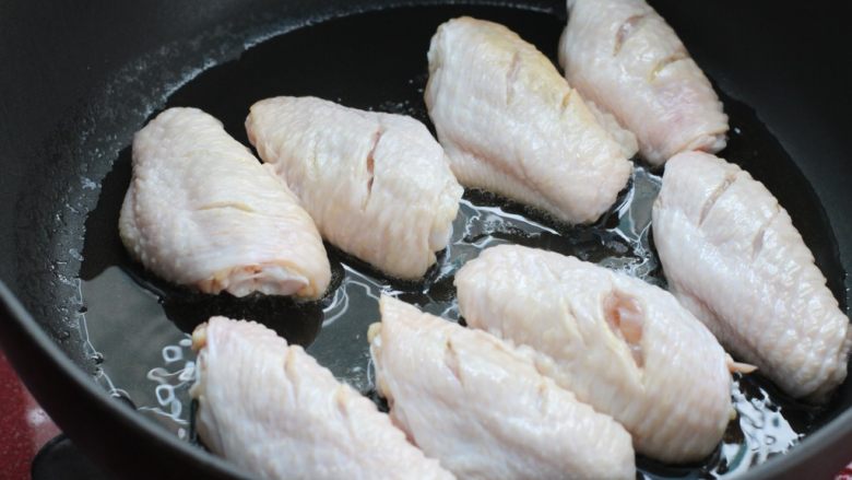 红烧鸡翅炖土豆,锅中倒适量食用油烧热,鸡翅中用厨房纸擦干多余水分放入锅中