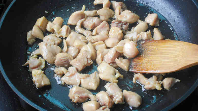蚕豆炒鸡丁,炒锅中加油烧热,放入鸡丁炒变色