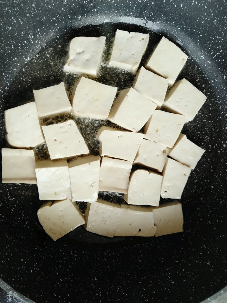 肉末烧豆腐,锅内倒入适量食用油,把切好的豆腐码平,煎至底部金黄色。