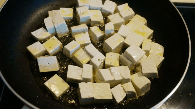 煎豆腐,平底炒锅中倒适量油,油温热时,倒入豆腐块,平铺在锅底;