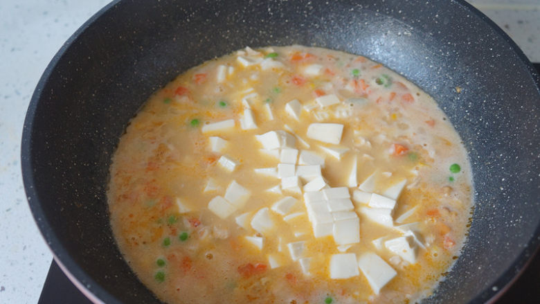 咸蛋虾仁豆腐煲,水开后倒入豆腐,小火煮三四分钟