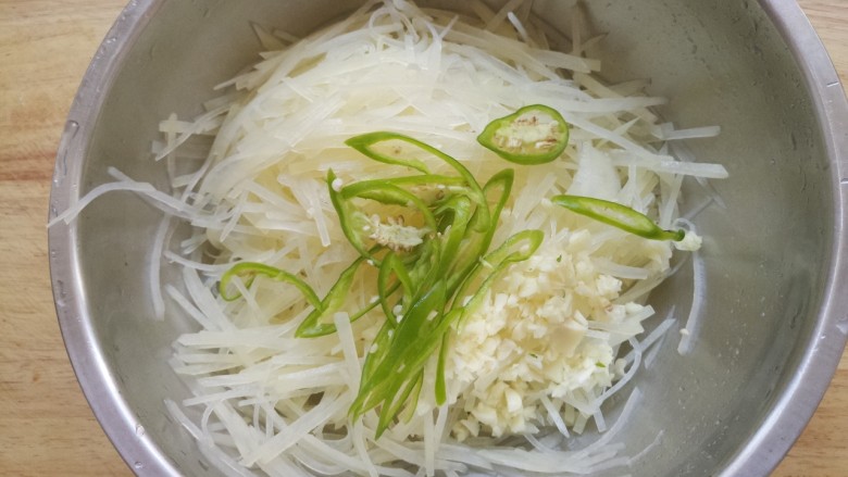 凉拌青椒土豆丝,把土豆丝,青椒丝和蒜末放在一个盆里。