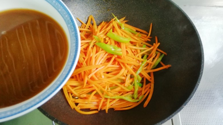 鱼香胡萝卜丝,将调好的鱼香汁搅拌后倒入炒锅中