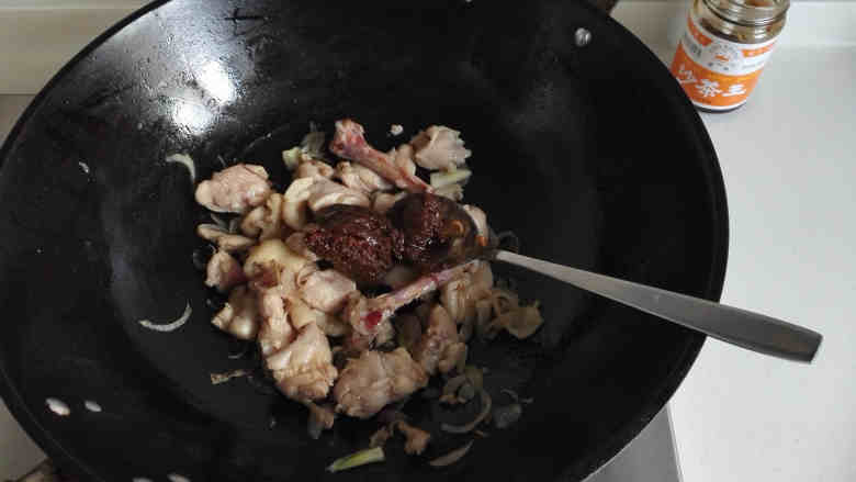 鸡腿焖饭,炒至鸡腿肉收缩变色后,放入2大勺沙茶酱,炒匀