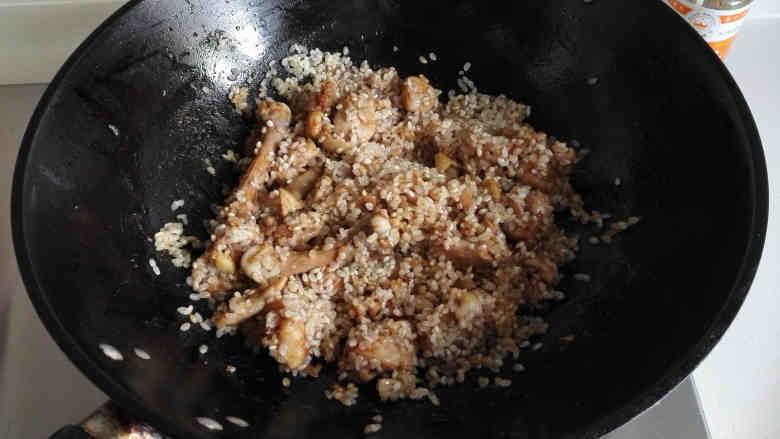 鸡腿焖饭,放入用生抽拌匀的大米,翻炒几下沾满锅中的酱汁