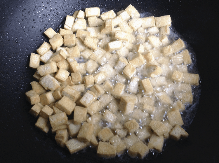 爆炒三丁,白豆腐干洗净切丁,炒锅内加4大勺油烧热, 把豆腐干丁炸至金黄后捞出。