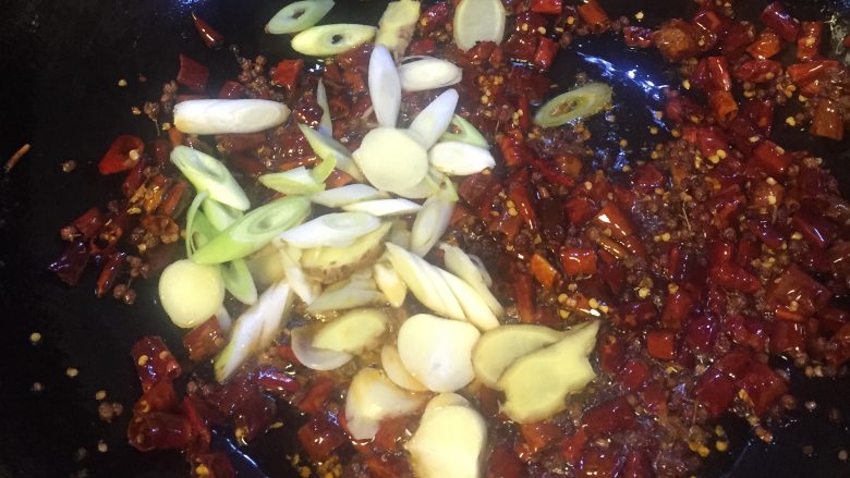 香辣小龙虾,下油烧热,倒入干辣椒、干花椒翻炒20秒后,下葱、姜、蒜快速炒香