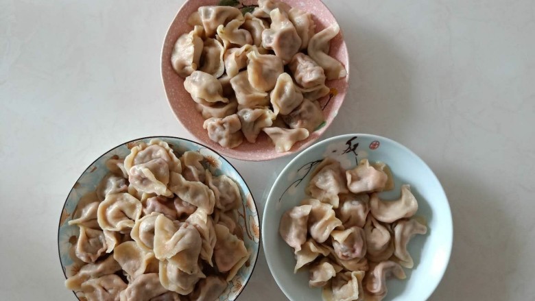 苋菜猪肉饺子,锅中放入适量水,水开后下入饺子,用勺子扣着,留着锅底划2下,煮至透明,捞入盘中。