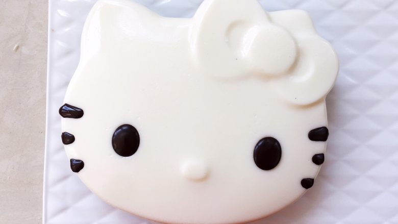 Hello kitty蜜豆牛奶冻,冰箱取出冷藏的蜜豆牛奶冻,在凹下的眼睛跟胡须处挤满黑巧克力。