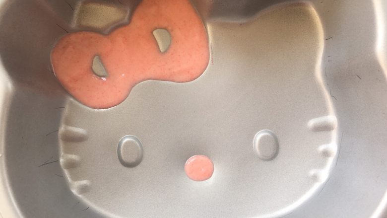 Hello kitty蜜豆牛奶冻,模具垫平,在蝴蝶结跟鼻子凸起的部分挤上适量的巧克力。之后入冰箱冷冻1分钟至巧克力凝固。
