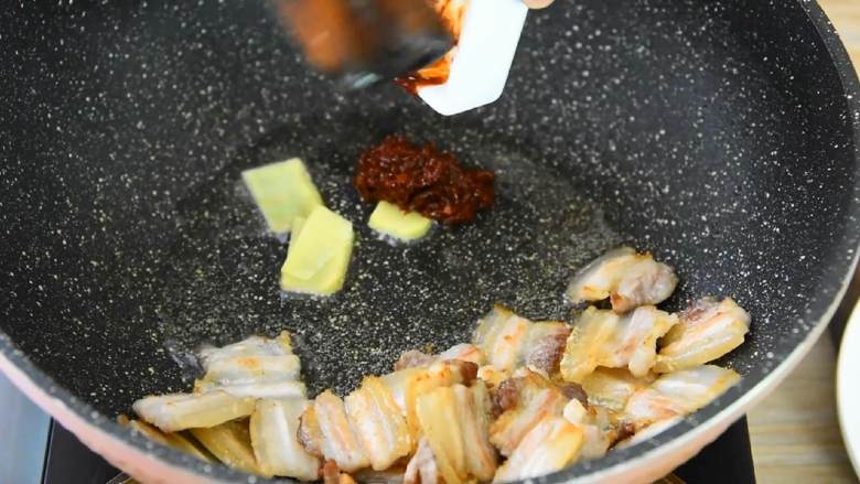 回锅肉-圈粉无数的川菜,自己来做一次试试吧,五花肉推至锅边,倒入姜片、豆瓣酱炒出红油。