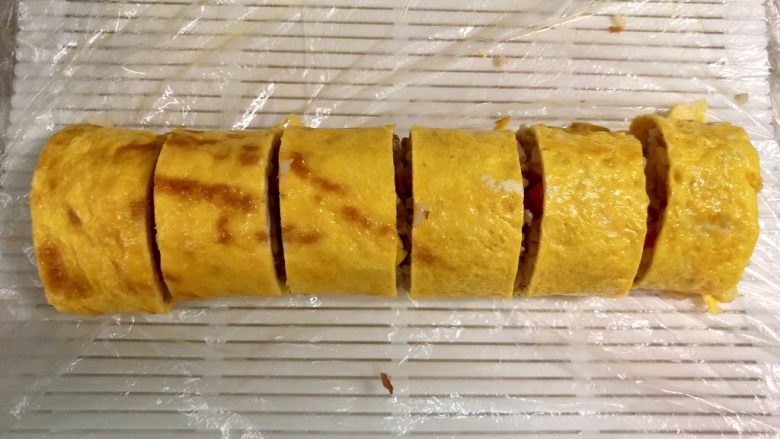 培根时蔬米饭鸡蛋卷,打开寿司席,把蛋卷切成2cm左右的小段。