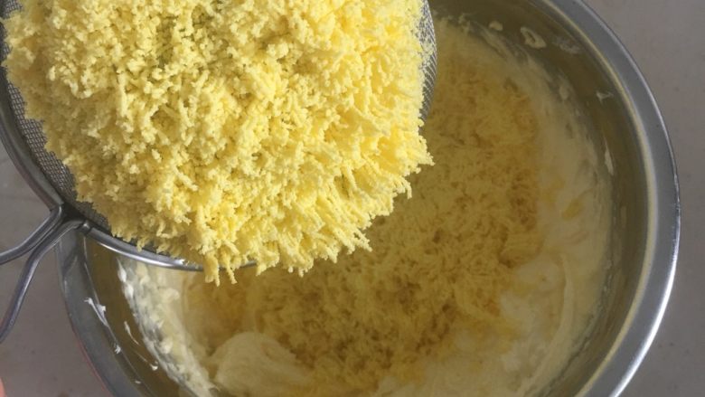 火龙果蛋黄奶豆,用打蛋器把黄油打发微微发白,加入过筛的熟蛋黄,一起打发均匀