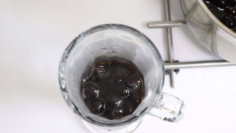 网红脏脏茶,不排队也能喝,离火后,用勺子挖出适量的珍珠糖浆,倒入准备好的杯子中。