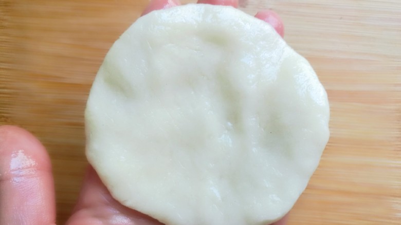 炸糖糕,取一个小剂面团用手掌按扁,然后轻捏边缘成一个圆饼。