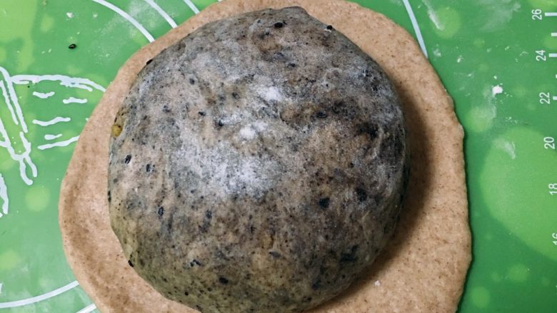 芝麻核桃黑麦包,芝麻核桃面团滚圆,放入大的饼中,包裹起来,这样做就是要外观漂亮。