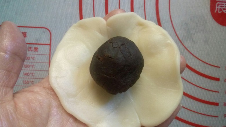 老婆饼(豆沙版),包入红豆沙馅,还是用虎口的手法包紧,收口捏紧,朝下放置,用手轻轻按扁,用擀面杖擀成椭圆形。