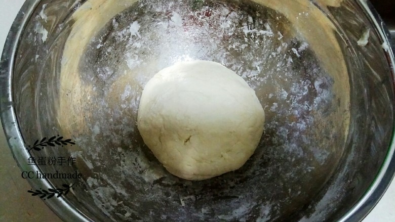 家常葱油饼,2 在上述棉絮状的面粉里加入冷的饮用水。饮用水可以提前半小时放入冰箱冷藏,如果是冬天做的话就不用放冰箱。加入饮用水后,用手将面粉揉成表面光滑的面团。然后用保鲜膜将面粉团包好,室温静止30分钟,醒面。