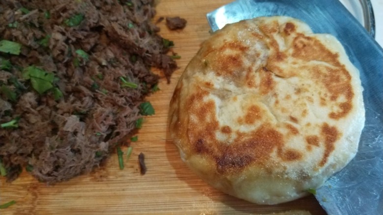 自创多味烧饼加驴肉,烧饼用刀劈开。