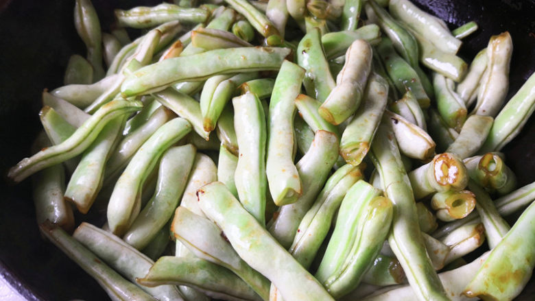 脊骨土豆炖豆角,接着倒入豆角翻炒至变色,这里要说的是豆角一定要炒熟才能吃哦,否则会中毒的,