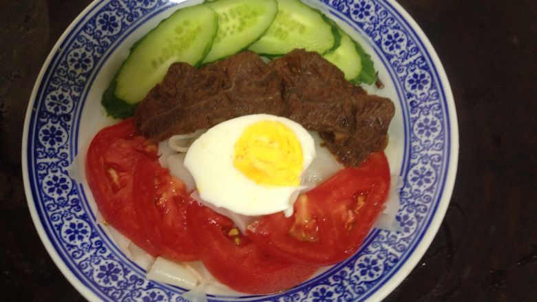 凉皮新吃,碗底部放入凉皮,上面摆黄瓜、牛肉、番茄和半个煮熟的鸡蛋