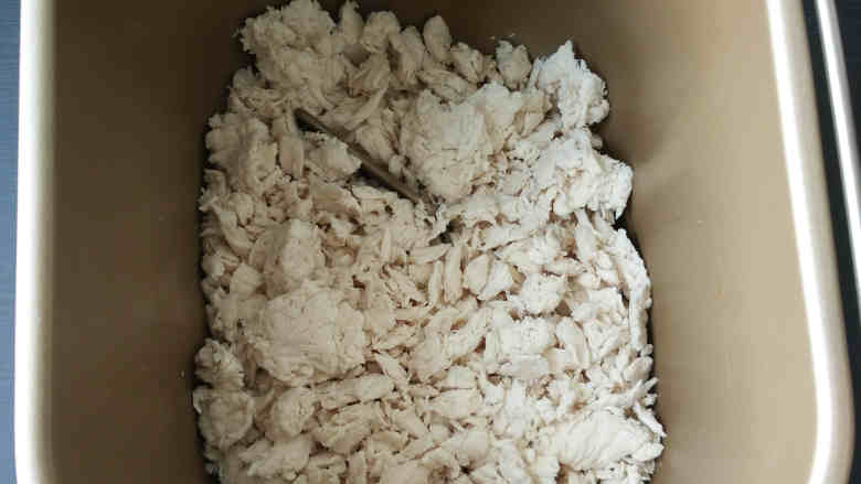 沙茶酱肉松,将压碎的鸡胸肉倒进面包桶里,面包桶需事先装好搅拌棒;