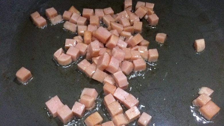 小孩最爱的下饭菜:火腿玉米毛豆杂炒,适量油加热,放入火腿丁翻炒。