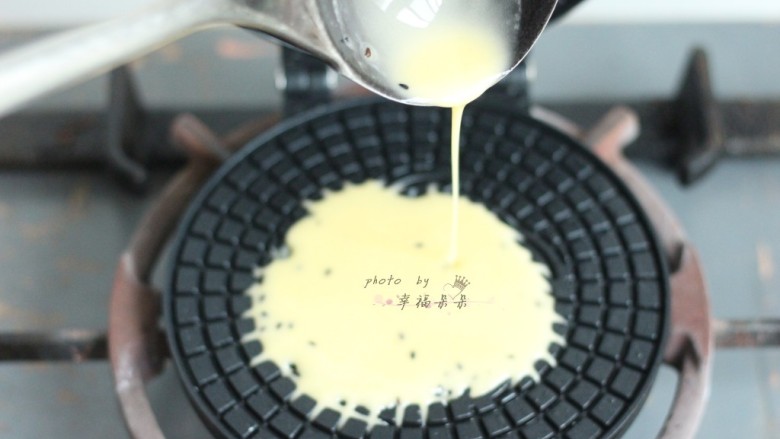 黑芝麻蛋卷,用勺子舀一勺面糊倒入蛋卷模具中间位置,面糊会自动朝旁边溢开,溢开至模具3/4圆周满时,立即合上蛋卷模,放在燃气灶上小火加热1分钟,然后翻过来模具反面加热40秒左右,直至蛋卷呈微黄色