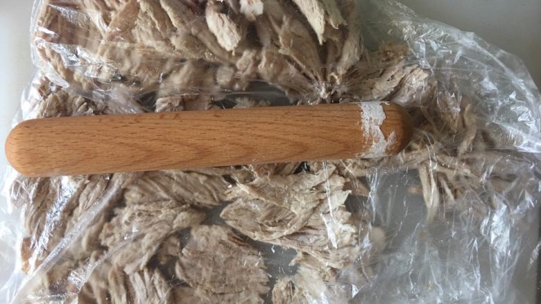 自制肉松,装入保鲜膜,用擀面杖碾开,肉呈薄饼状