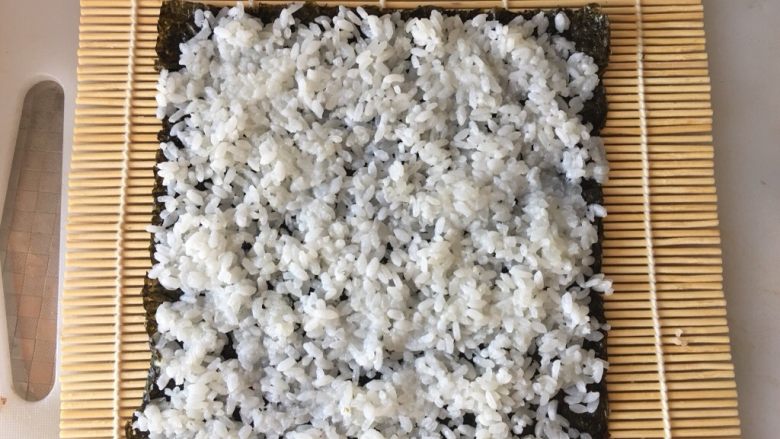 寿司,放入适量米饭,铺均匀,四周留出1厘米的空隙,不要铺太满太厚
