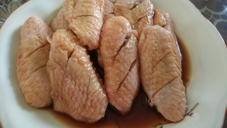 可乐鸡翅,鸡翅正反面各划两刀,加入料酒一勺,生抽一勺,老抽小半勺,抓匀放至冰箱30分钟进行腌至,中间可以翻一次面,让鸡翅充分入味