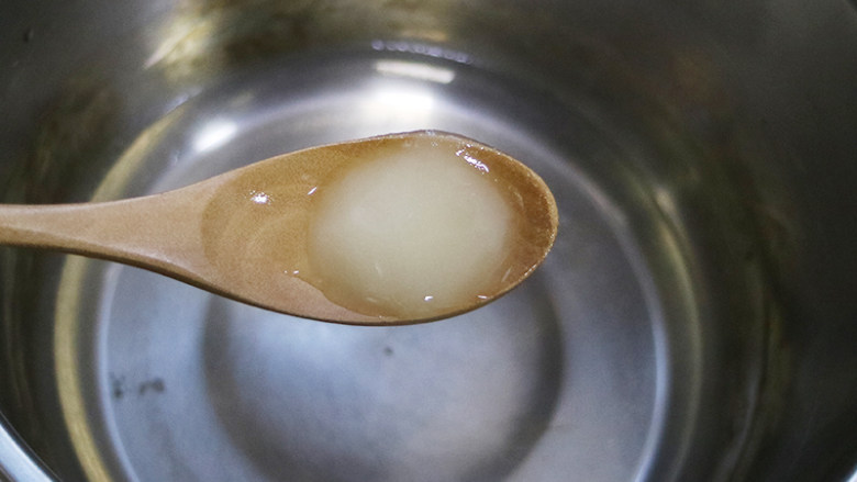 美丽甜品水晶草莓冻,小锅中倒入清水烧开后加入粉色糖果,煮到糖果融化,再倒入一个碗中,加入一勺子<a style='color:red;display:inline-block;' href='/shicai/ 865'>蜂蜜</a>,将其溶解开。