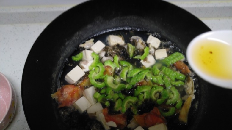 花蛤豆腐苦瓜汤,煮30秒，关火加入适量盐、<a style='color:red;display:inline-block;' href='/shicai/ 847'>香油</a>搅拌均匀。