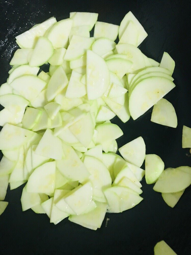 海米茭瓜,锅内热油,放入蒜瓣,茭瓜去皮洗净切片入锅